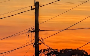 a telephone pole and wires against a sunset sky