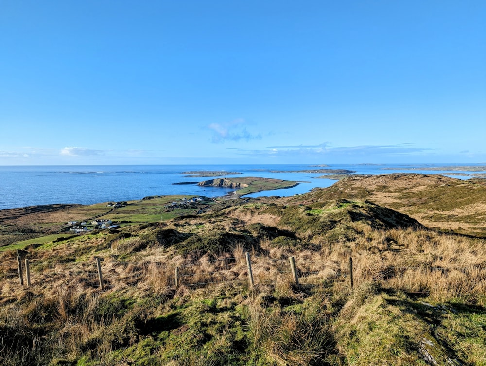 a grassy hill with a body of water in the distance