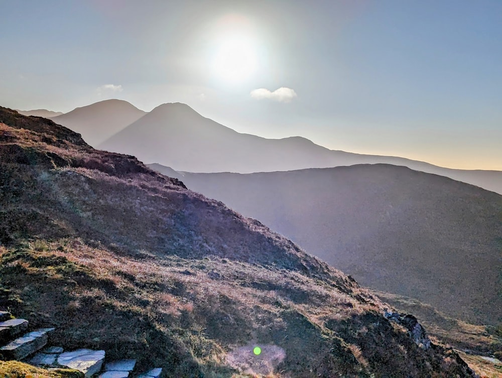 the sun is shining over a mountain range