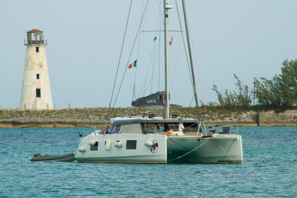 a sailboat in the water with a lighthouse in the background