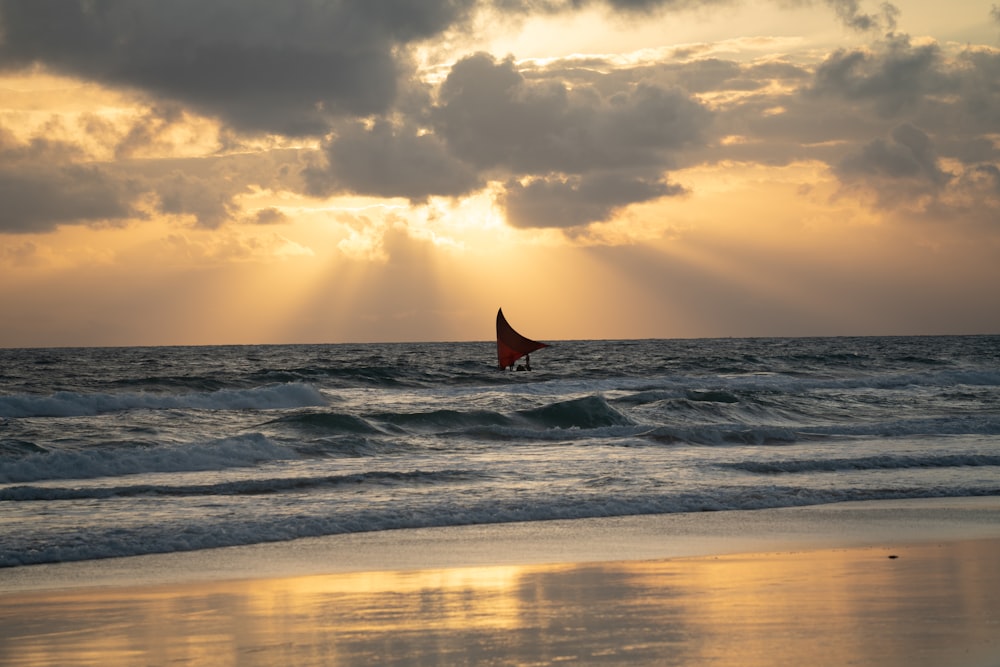 a person windsurfing in the ocean at sunset