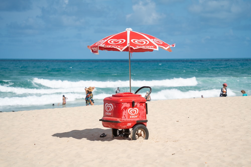 a red cart sitting on top of a sandy beach