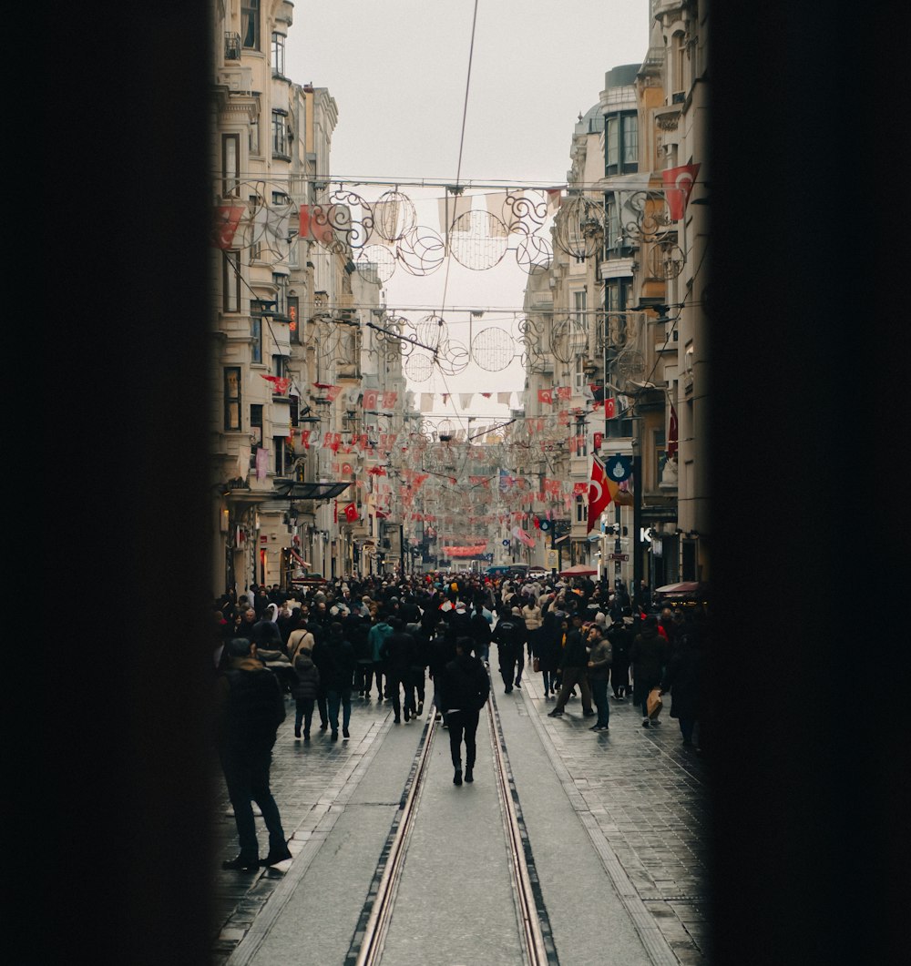 a crowd of people walking down a street next to tall buildings