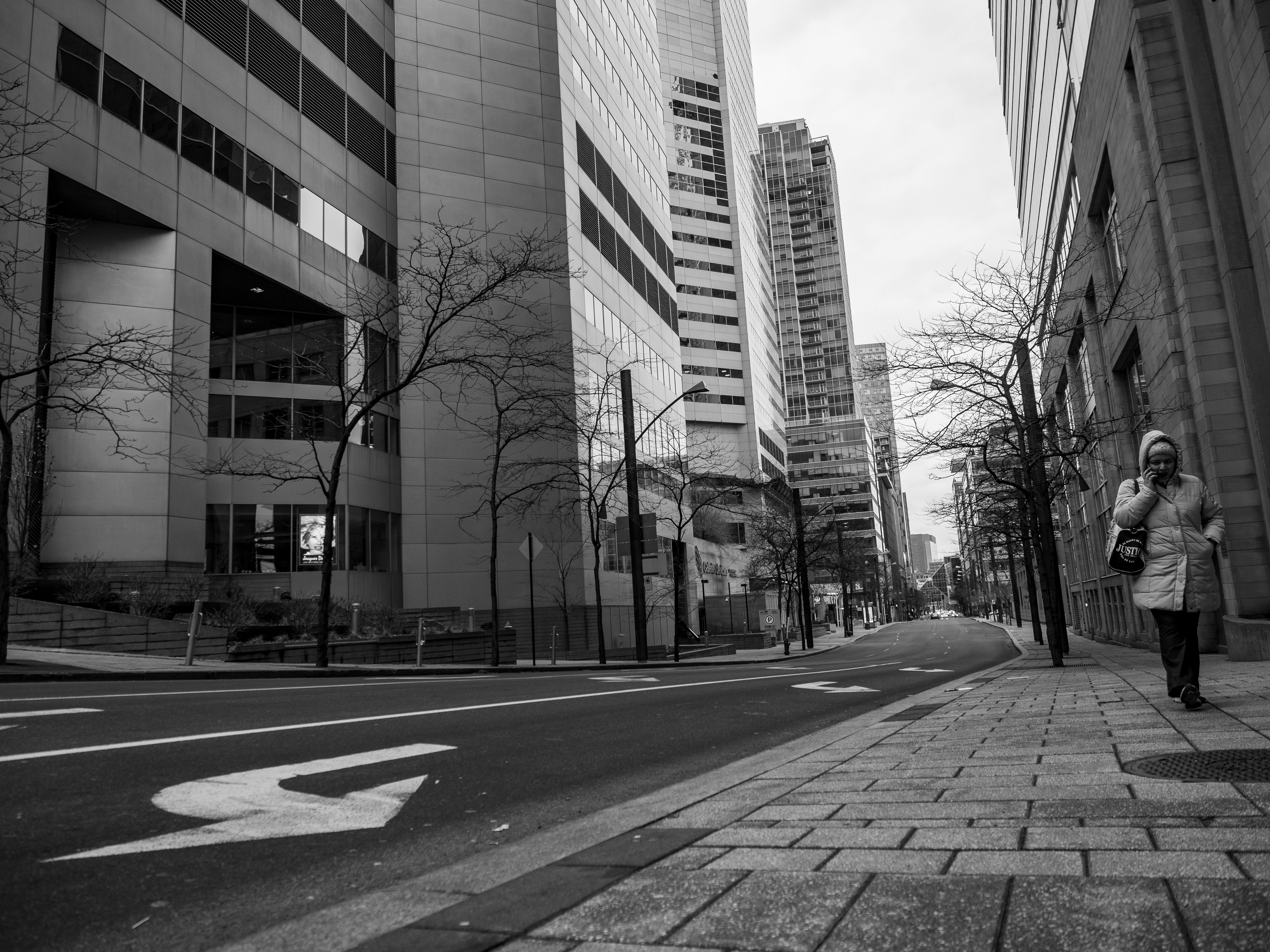 uma mulher caminhando por uma rua ao lado de edifícios altos