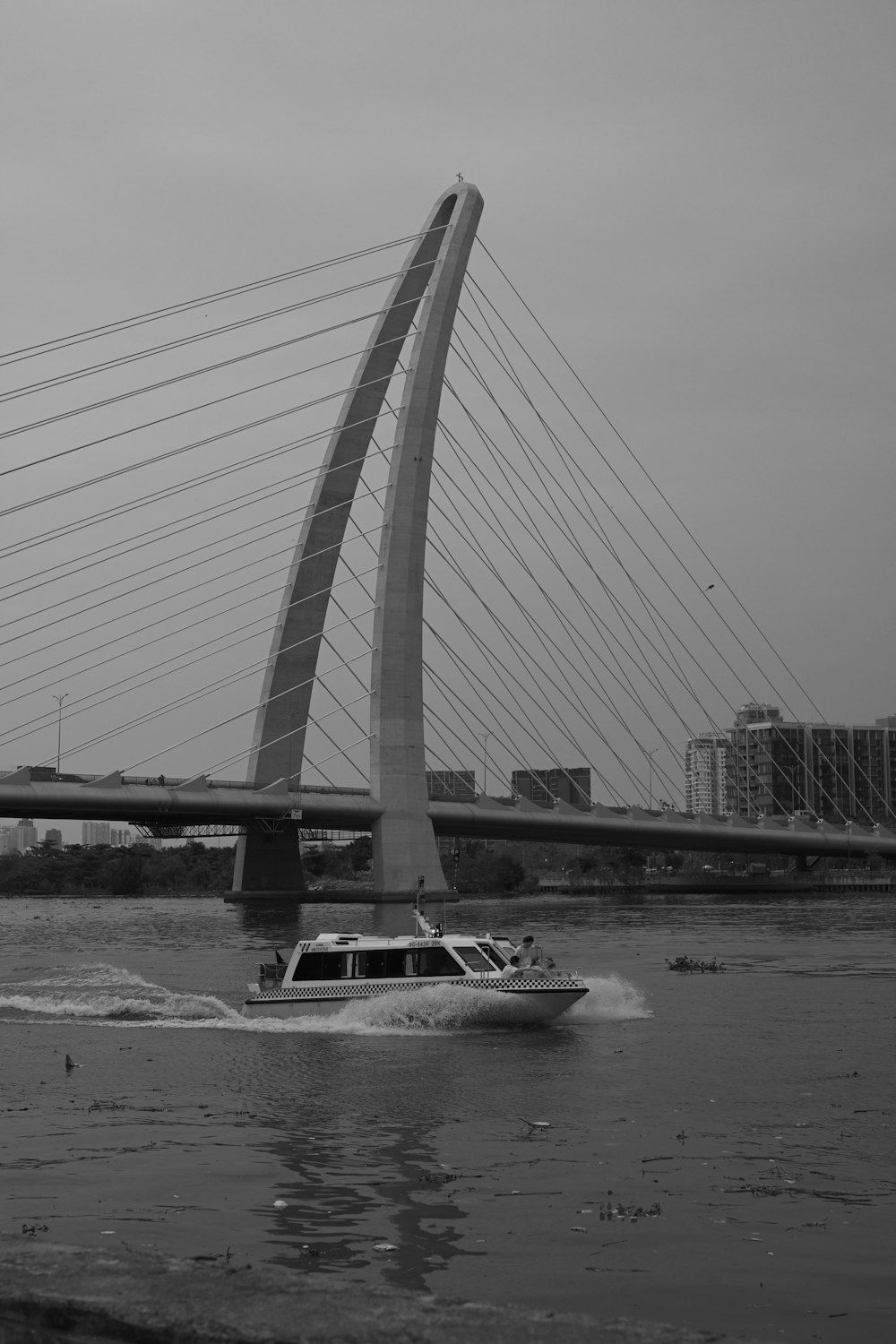 a black and white photo of a boat going under a bridge