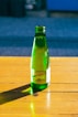 a green bottle sitting on top of a wooden table