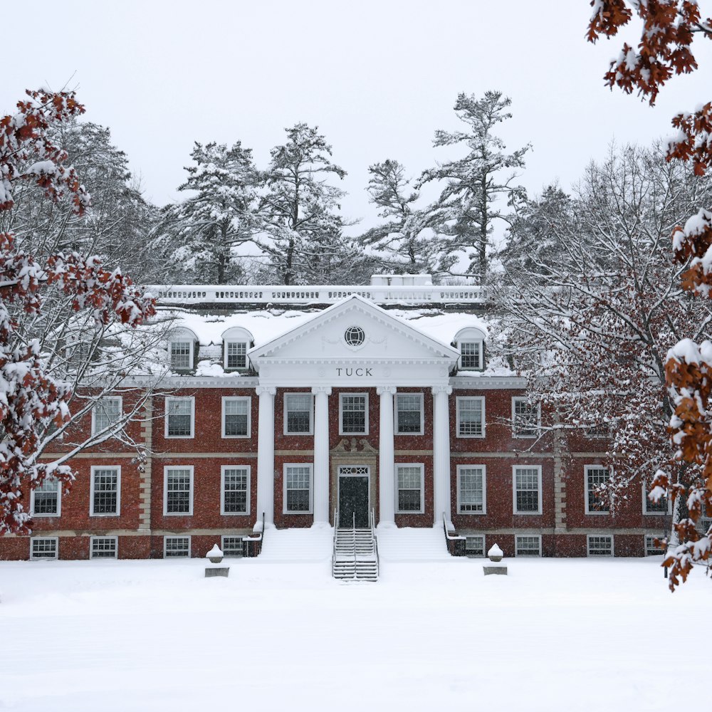a large red brick building surrounded by trees covered in snow