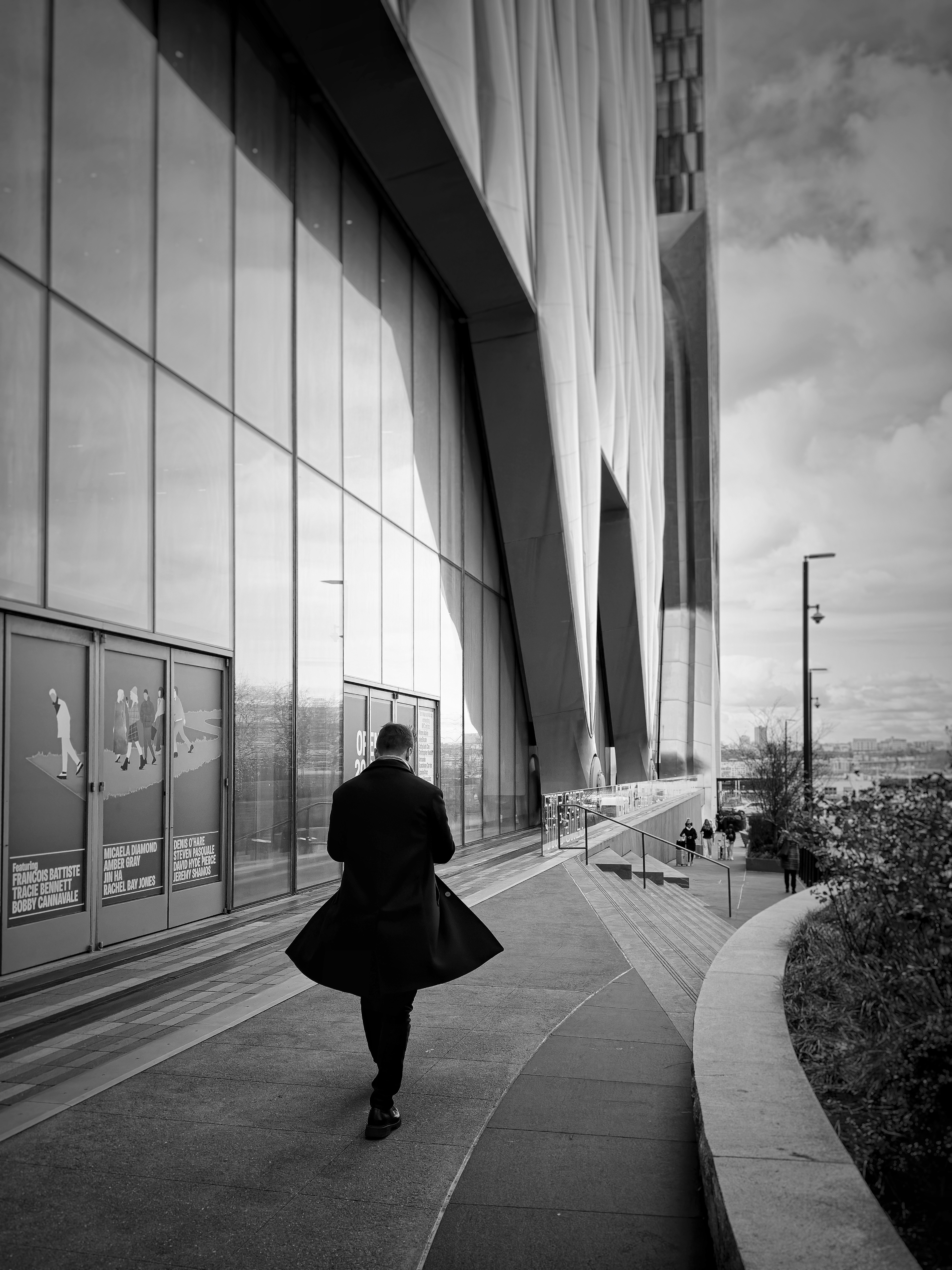 a man walking down a sidewalk next to a tall building