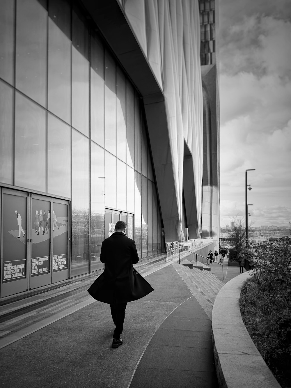 a man walking down a sidewalk next to a tall building