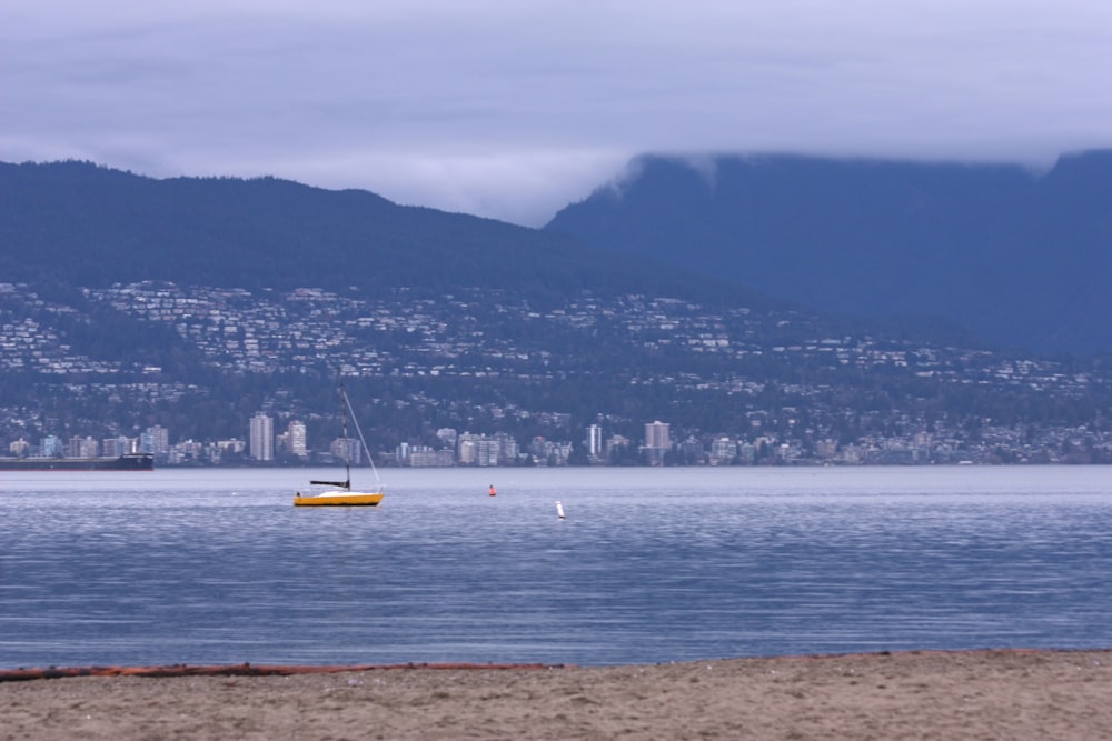 a sailboat on the water with a city in the background