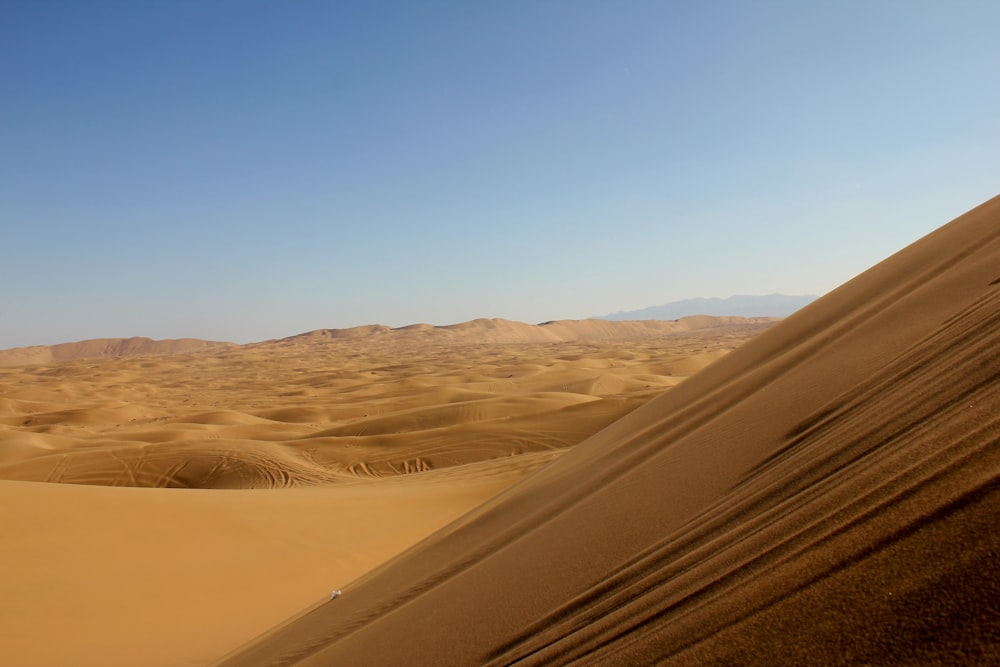 a desert landscape with sand dunes and mountains in the distance