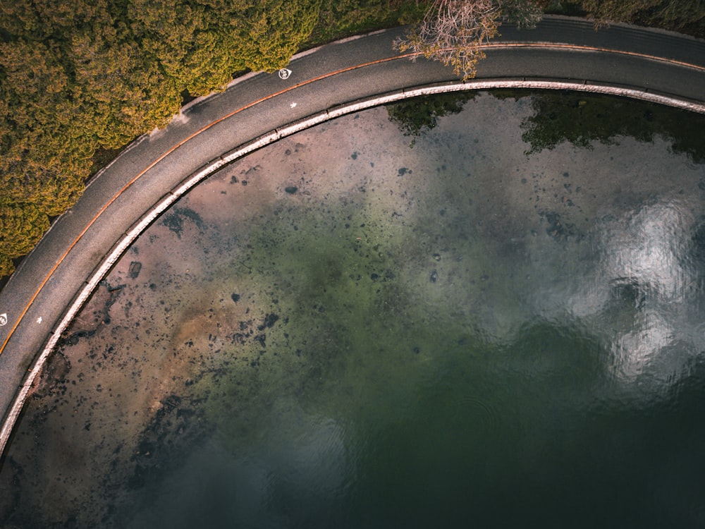 an aerial view of a curved road next to a body of water