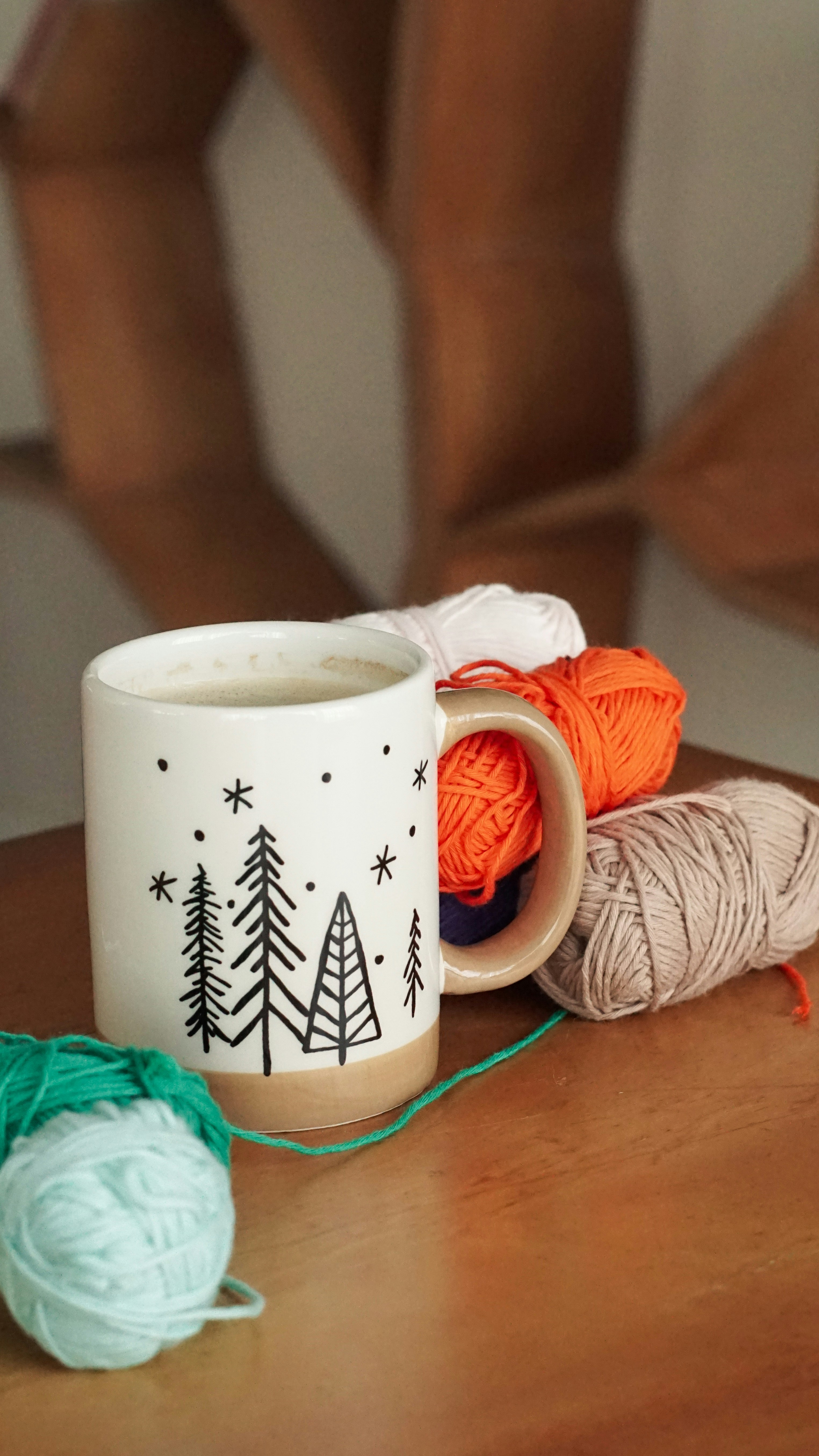 a coffee mug with a crochet ball of yarn next to it