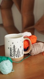 a coffee mug with a crochet ball of yarn next to it