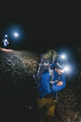 a man with a backpack and a flashlight in the dark