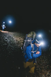 a man with a backpack and a flashlight in the dark