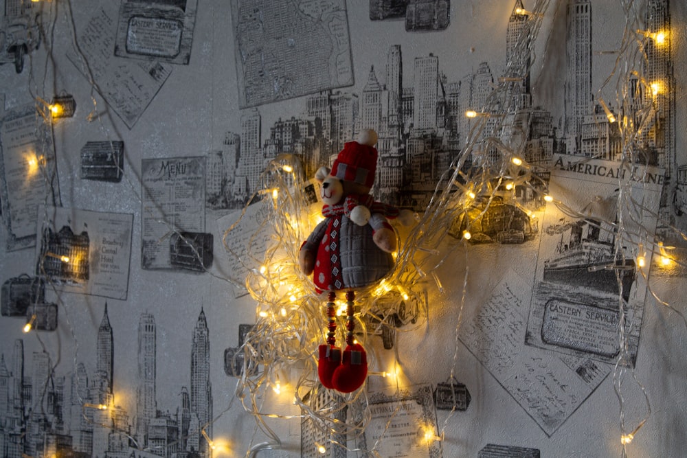 a teddy bear with a red hat and red mittens on a string of lights