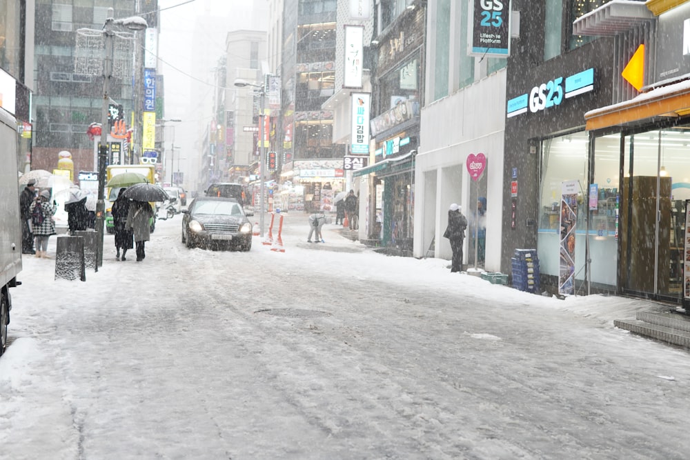 a city street is covered in snow as people walk on the sidewalk