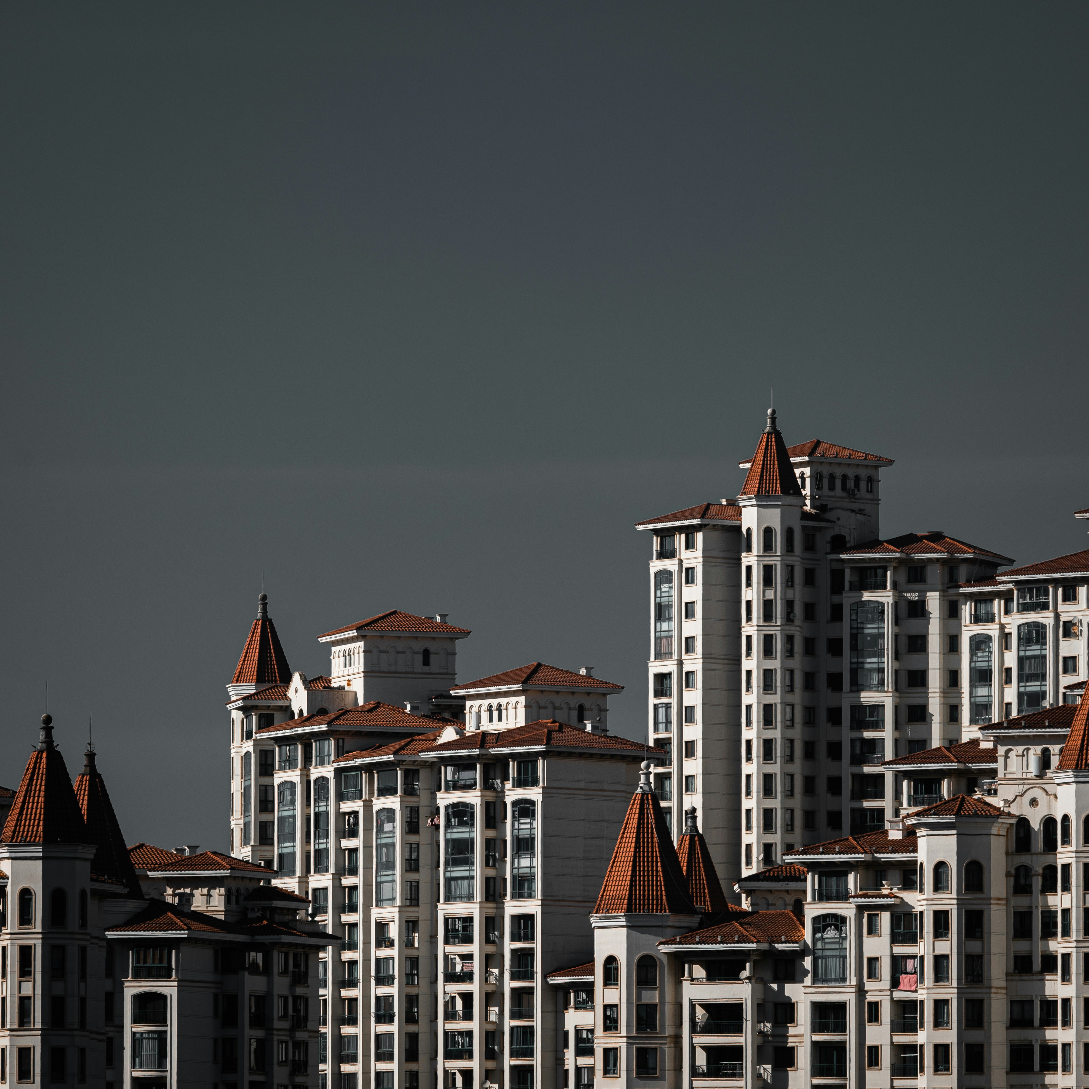 A large group of buildings with a plane flying in the sky photo – Free ...