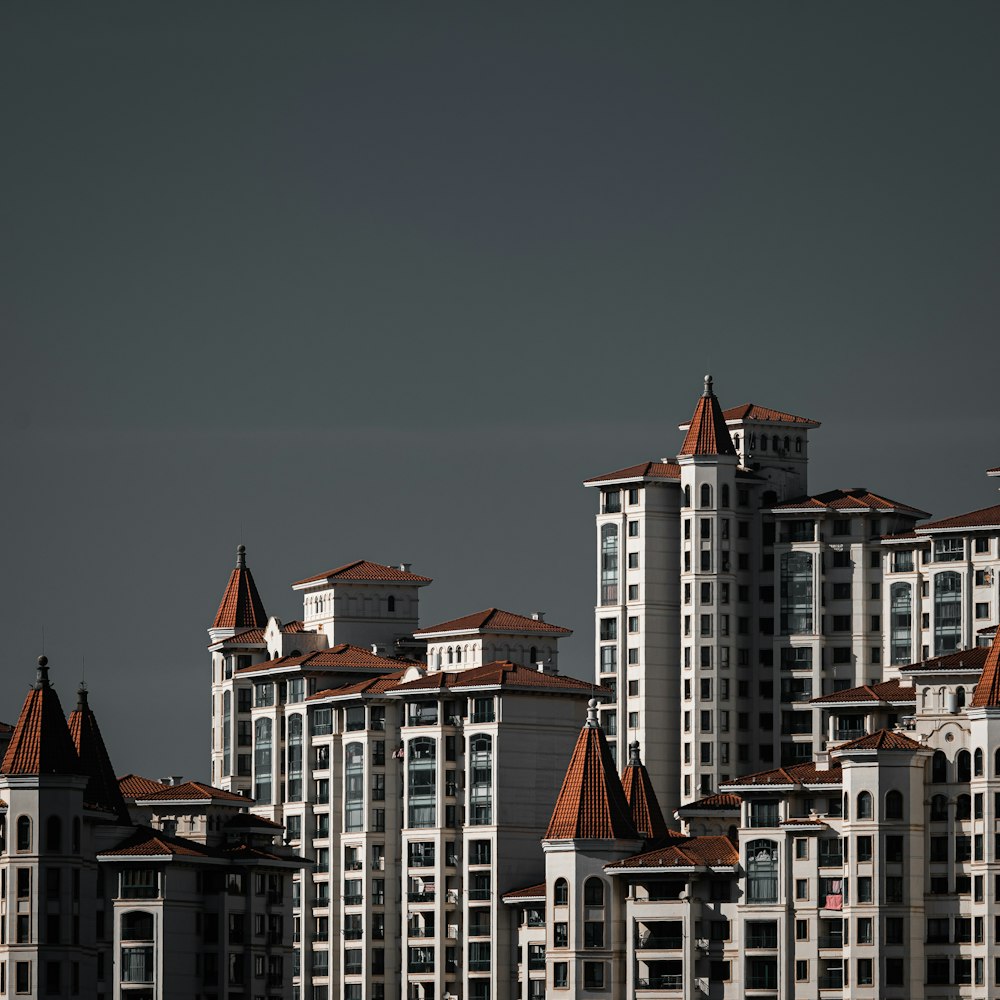 a large group of buildings with a plane flying in the sky