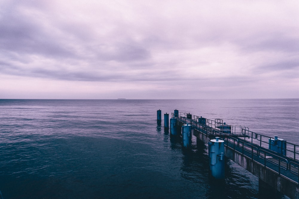 a long pier extending into the ocean under a cloudy sky