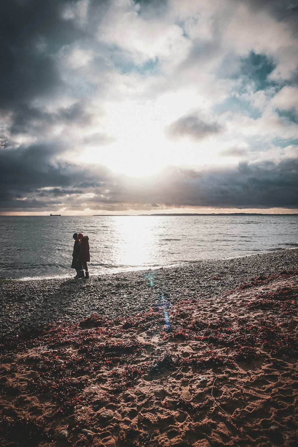 a couple of people standing on top of a sandy beach