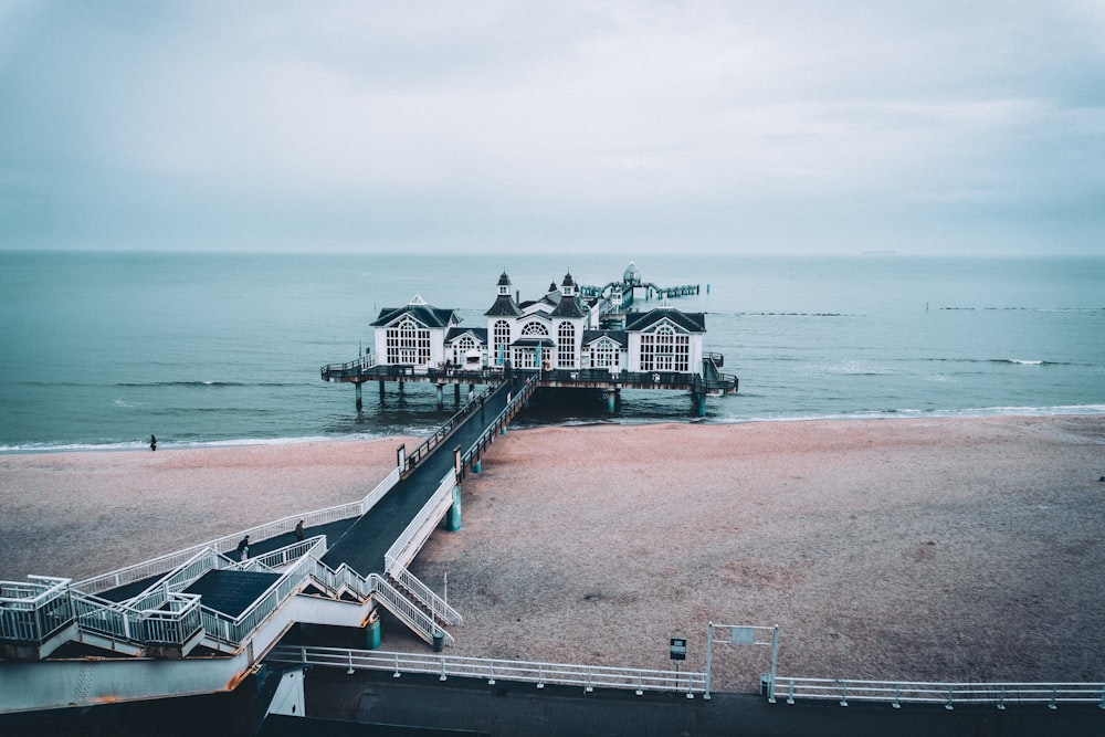a pier on the beach with a house on it