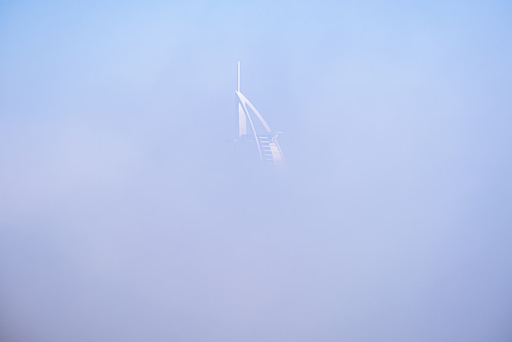 a plane flying in the sky on a foggy day