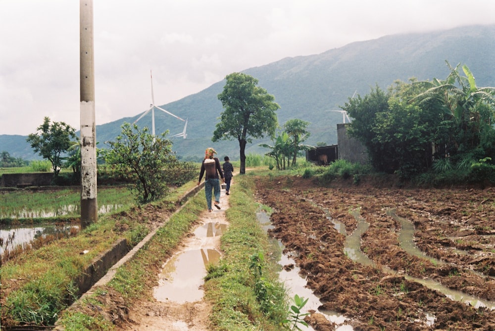 a couple of people walking down a dirt road