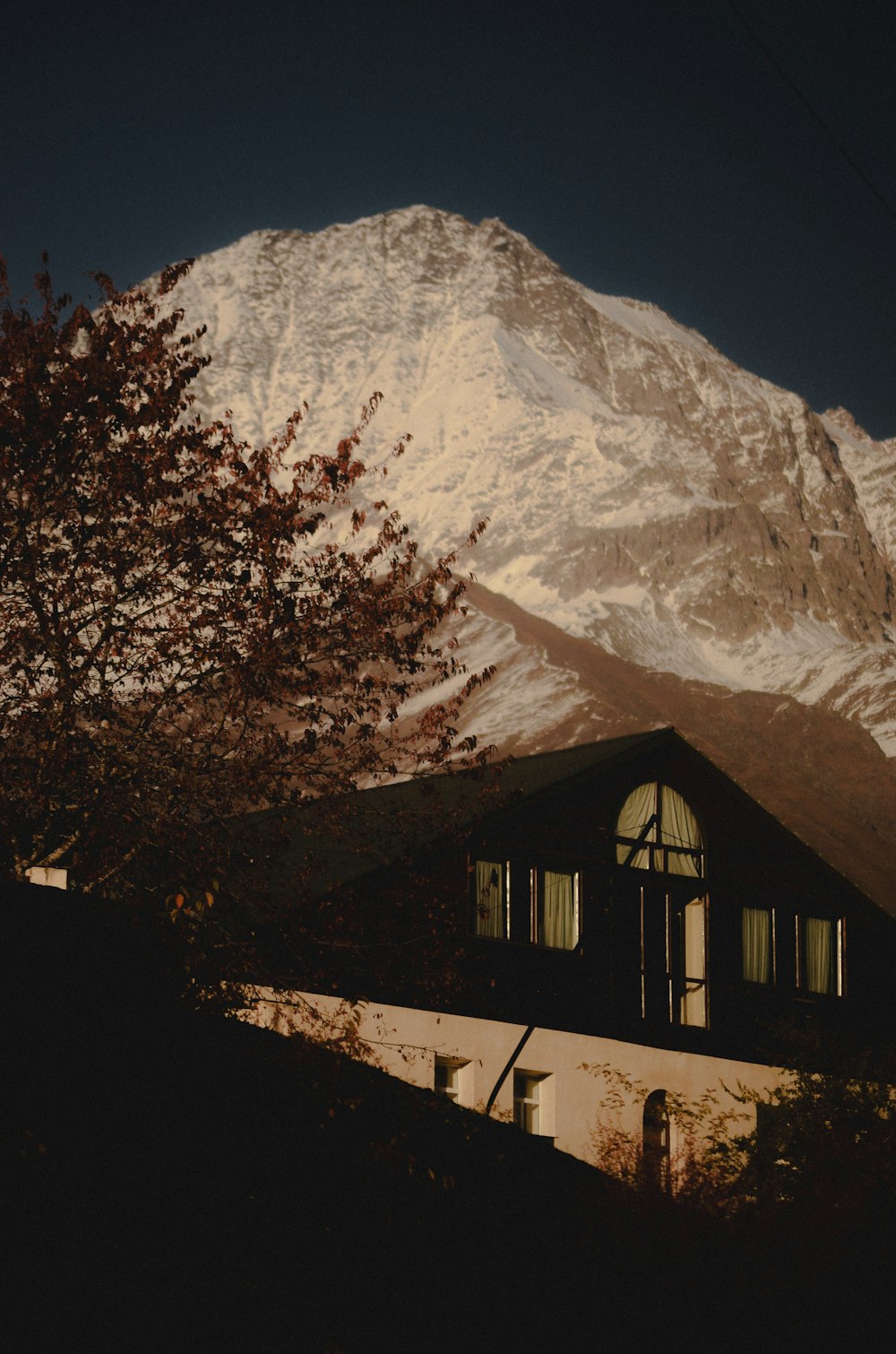 uma montanha coberta de neve com uma casa em primeiro plano