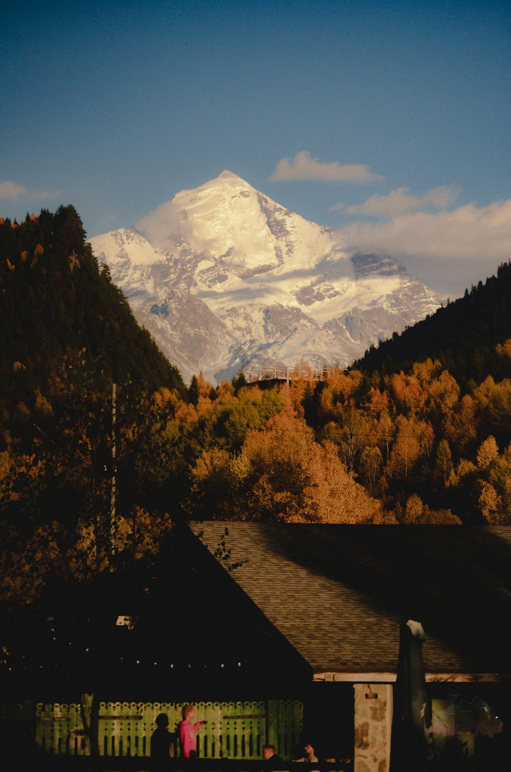 a snow covered mountain in the distance with a house in the foreground