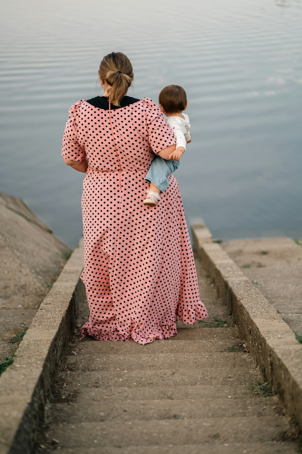 a woman holding a child walking down a flight of stairs