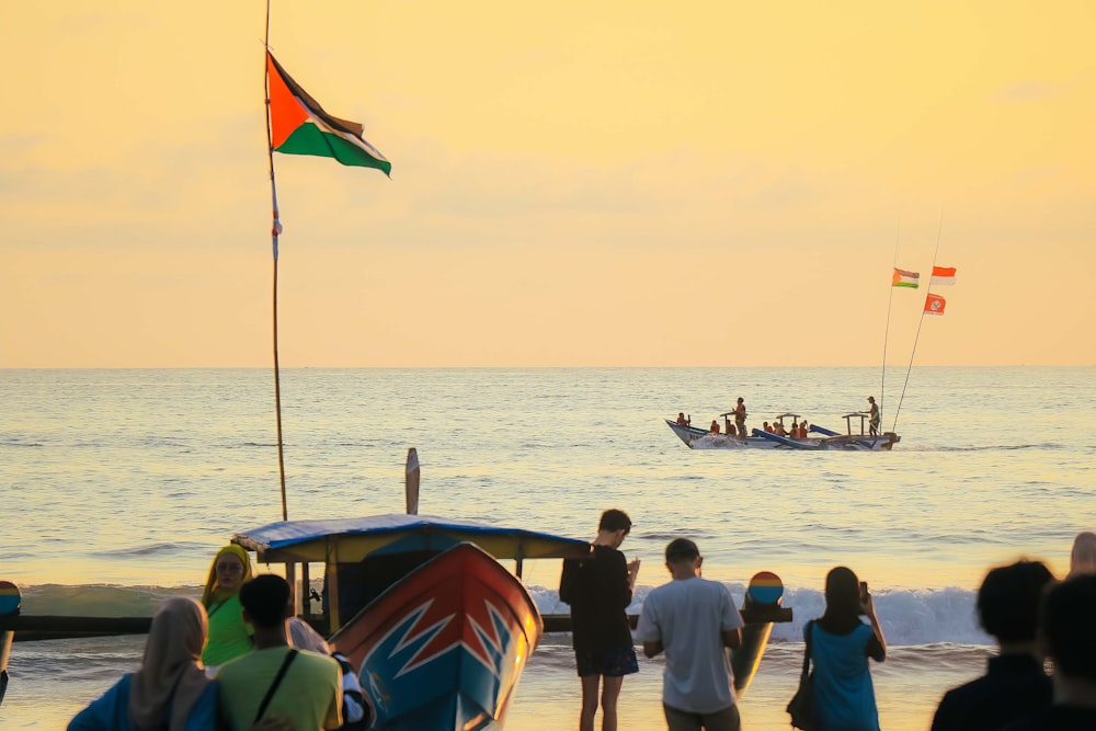 a group of people standing on top of a beach next to the ocean