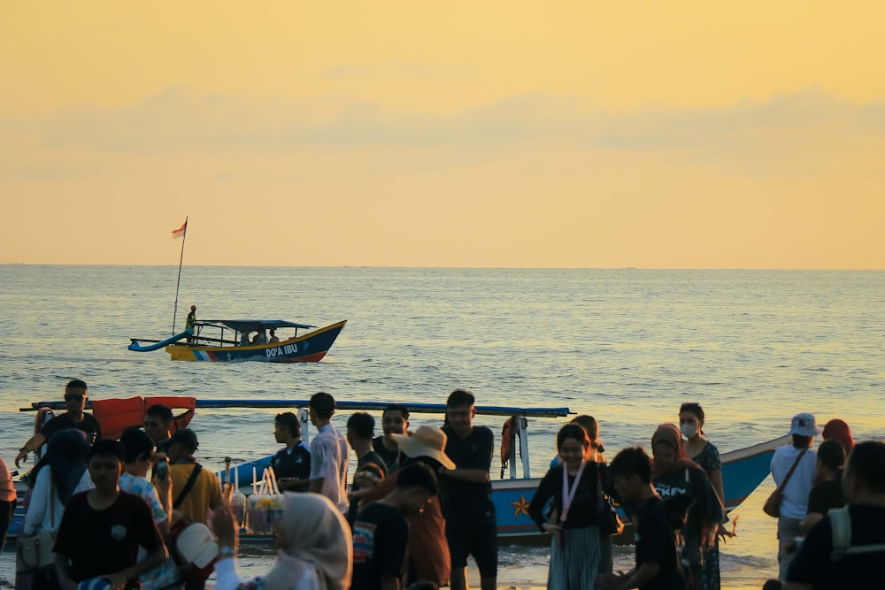 a group of people standing on a beach next to a boat