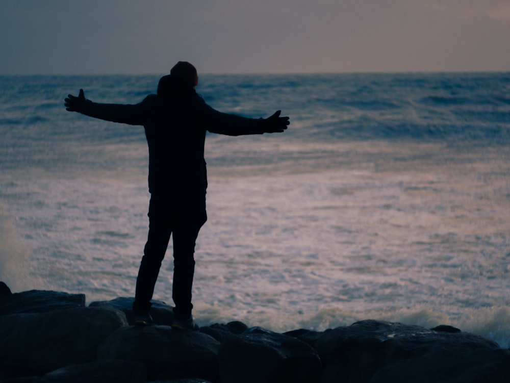 a person standing on rocks near the ocean