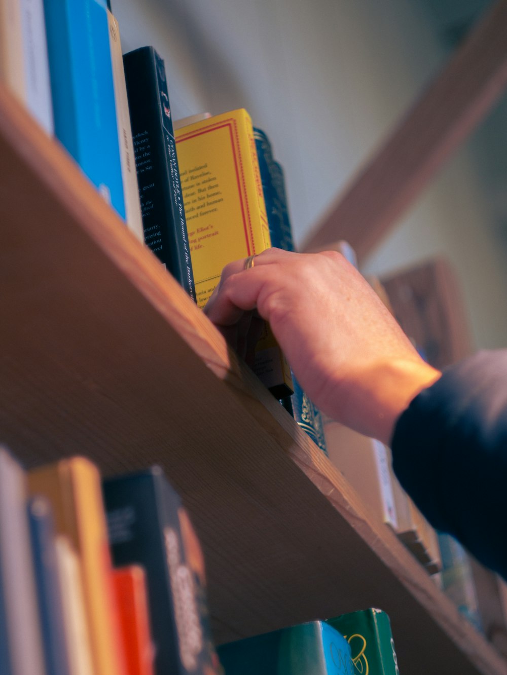 a person reaching for a book on a book shelf