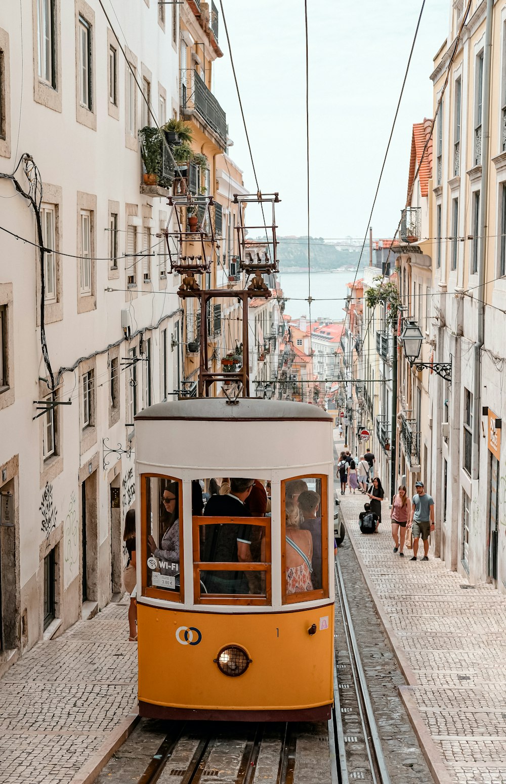 a yellow trolley car traveling down a street next to tall buildings