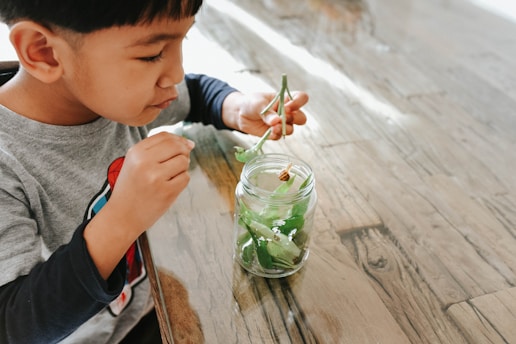 a young boy sitting at a table with a jar of water