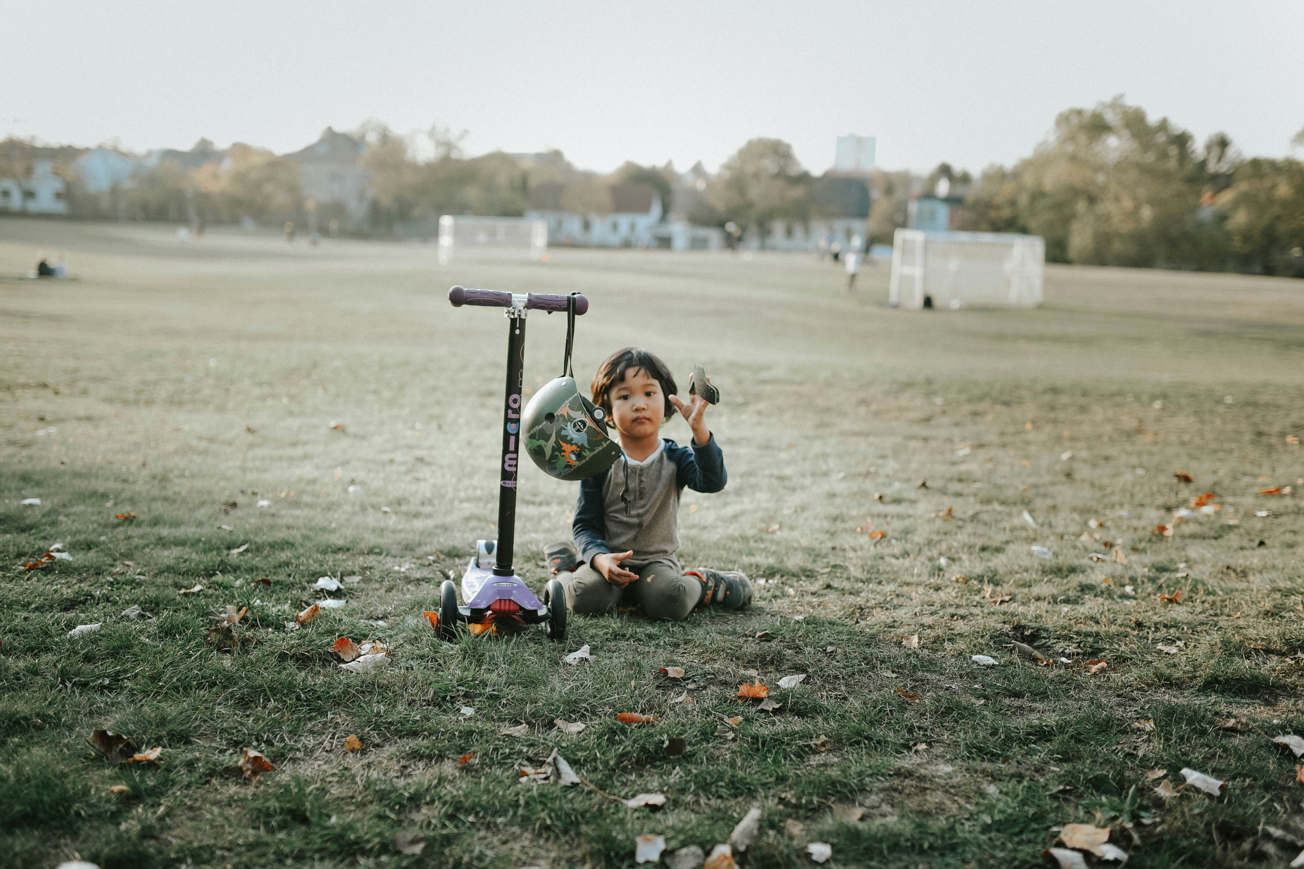 a young boy sitting on the ground next to a scooter