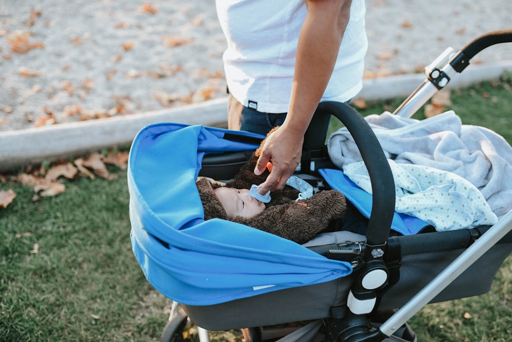 a baby in a stroller with a teddy bear in it