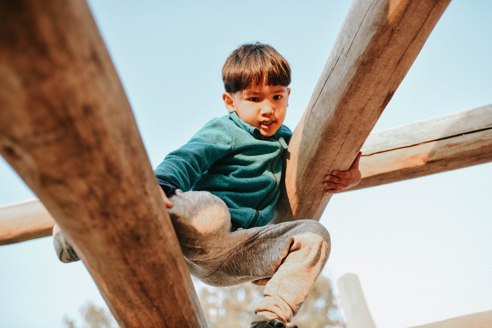 a young boy climbing up a wooden structure