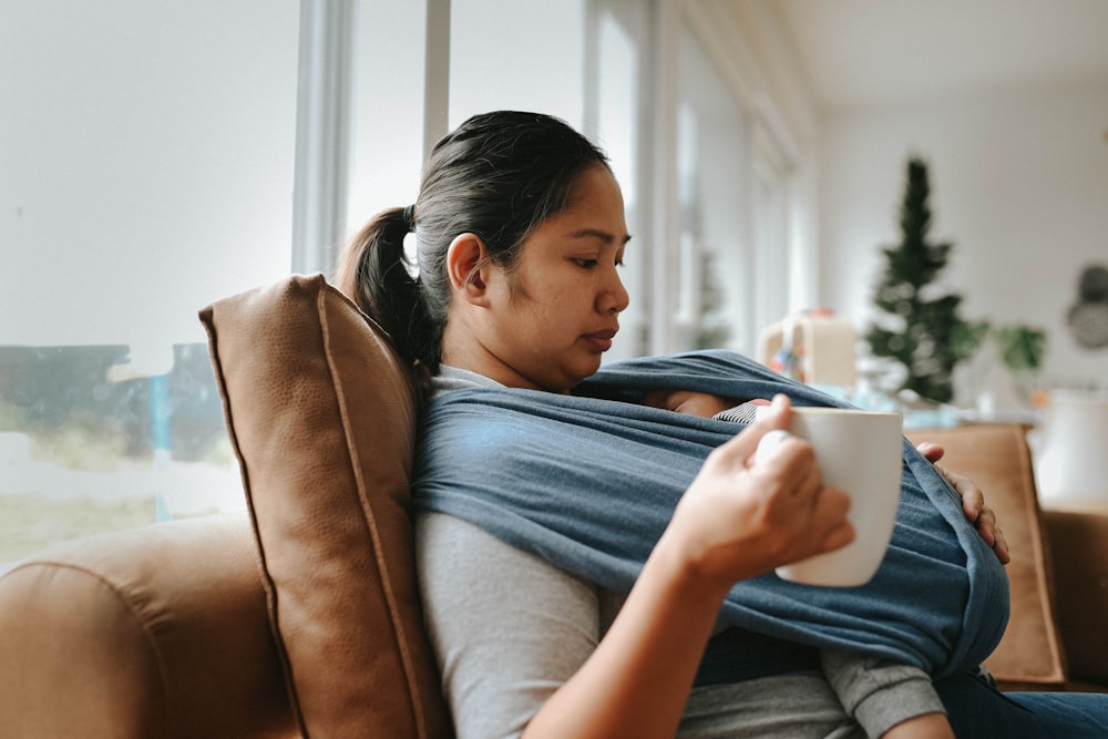 a woman sitting on a couch holding a cup