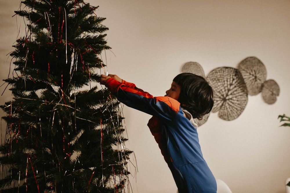 a young boy decorating a christmas tree