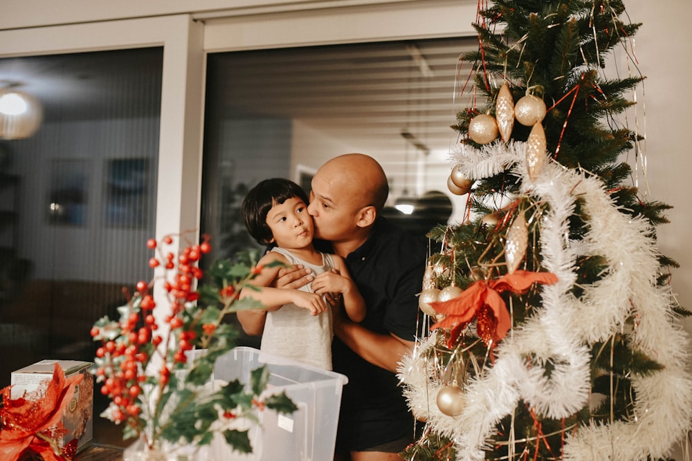 a man and a little girl standing in front of a christmas tree