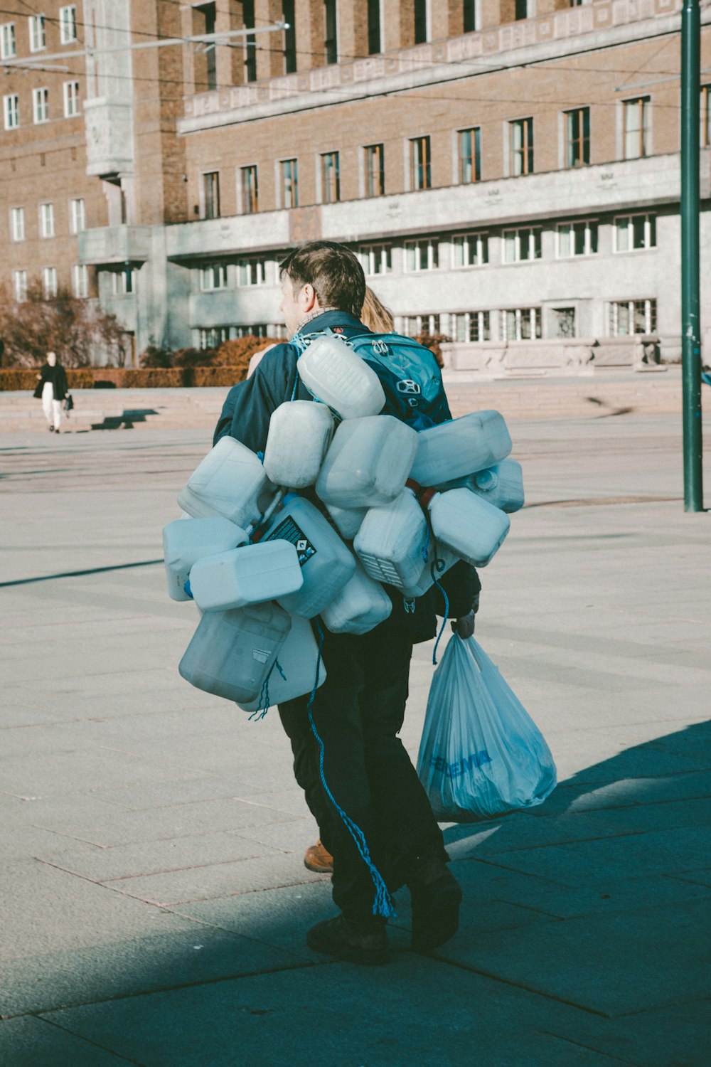a man walking down a street carrying a bag of stuff