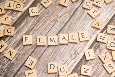 scrabble tiles spelling the word female on a wooden surface