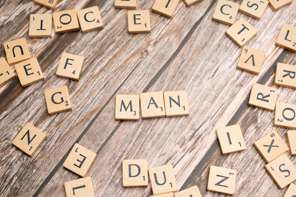 scrabble tiles spelling the word man on a wooden surface