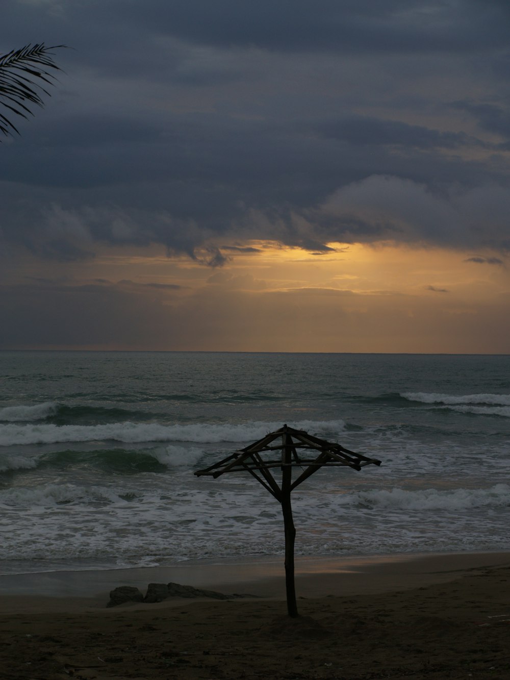 a wooden umbrella sitting on top of a sandy beach