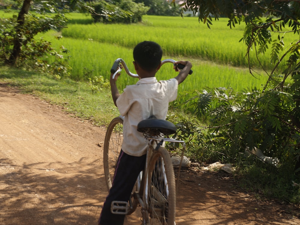 a young boy riding a bike down a dirt road