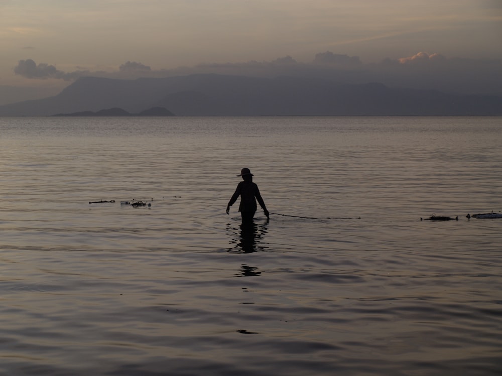uma pessoa em pé na água com uma prancha de surf